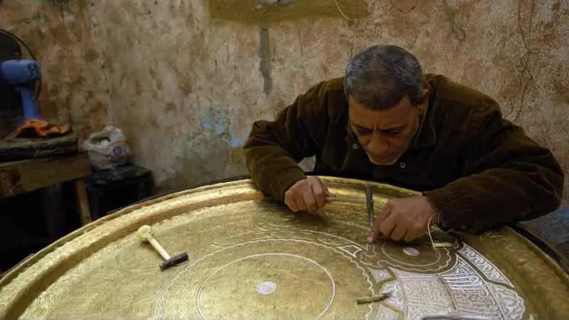 A craftsman inlaying silver into a brass tray